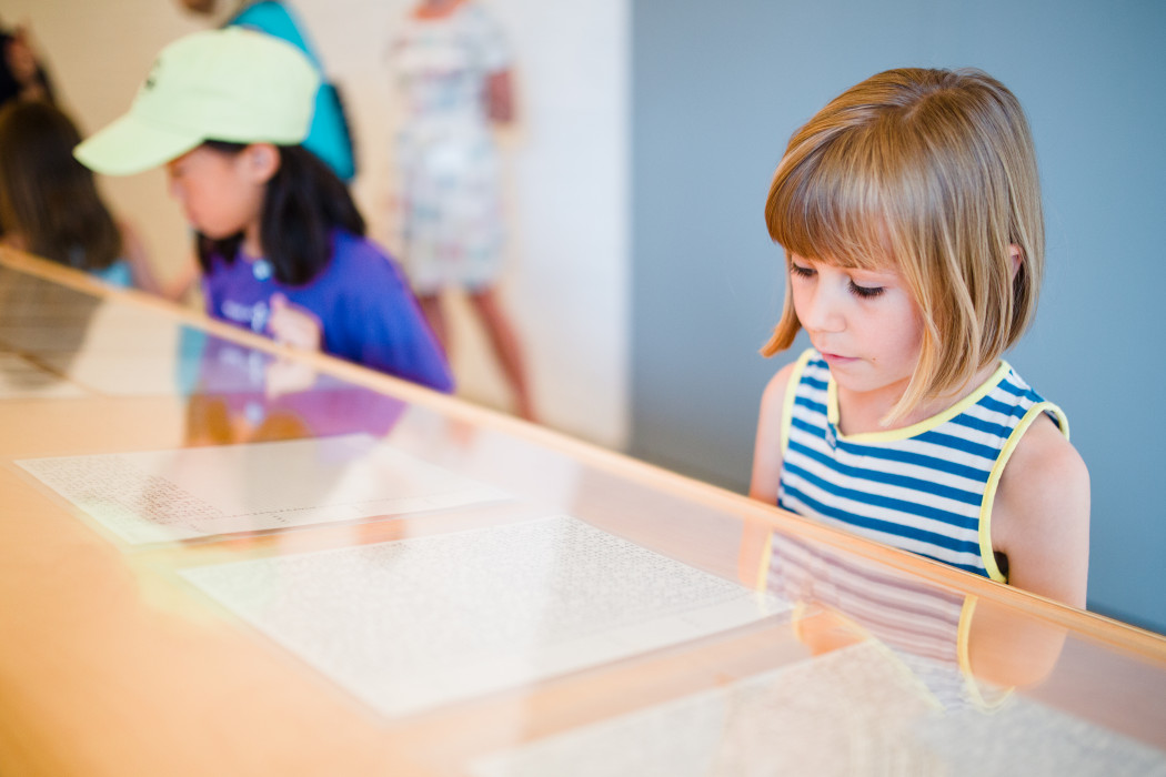 Two children viewing pieces of paper under glass.