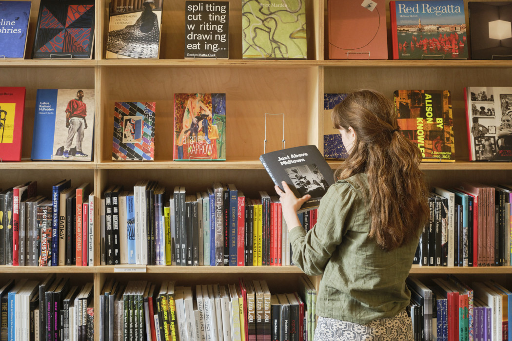 A person looks at a book in front of the floor to ceiling shelves of books in Dia Beacon's bookshop.