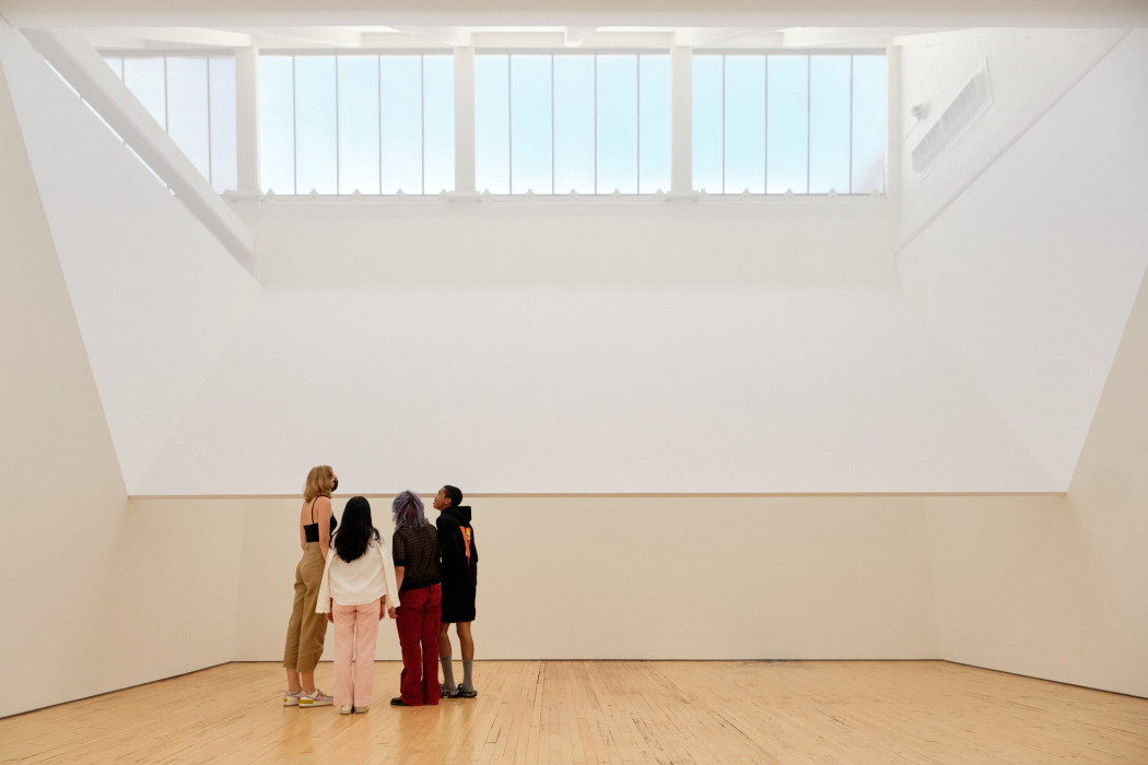 Four young people stand in front of a scrim that divides the room in half.