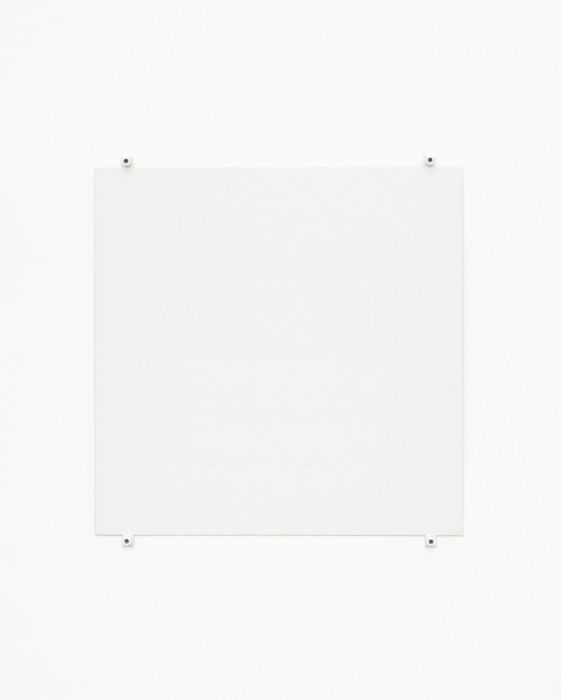 A white square hangs on a white wall using four white bolts and fasteners, affixed to the bottom and top of the work and near the corners.
