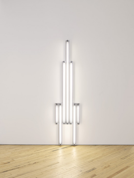 Seven fluorescent-white, tubular lights positioned against a white wall in the shape of a tower.