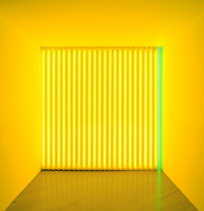 A square space is barricaded by several vertical yellow fluorescent tubes and one green tube on the right.