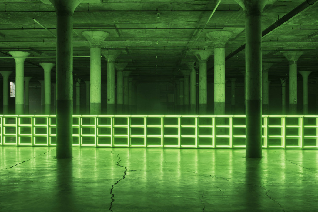 Green fluorescent barrier spans a large dark room with pillars.