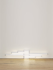Fluorescent white tubes of various lengths installed against a white wall close to the wood floor.