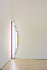 White, red, and yellow fluorescent tubes are mounted at the intersection of two walls.
