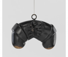 A black structure that resembles an upside-down U-shape with a leather-like overlay is suspended from a wire.