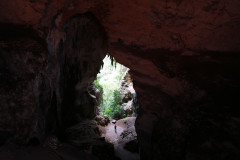 Interior of a cave. A small silhouette of a person in the center of the entrance of the cave.