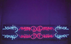 A dark purple room with a neon sign in loose handwriting that says 