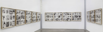 Multiple framed groupings of twelve black-and-white magazine covers hang on white walls.