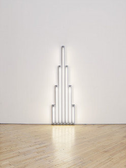 White fluorescent tubes mounted on a wall in the shape of a tower.