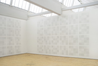 Two grids of drawings of squares within squares covering the space of two white walls. 