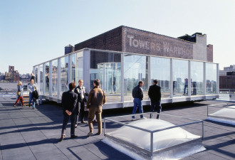 A large glass structure sits on a rooftop where people mill about.