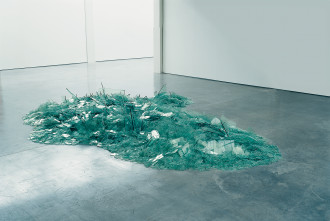 A pile of teal glass on a concrete floor. 