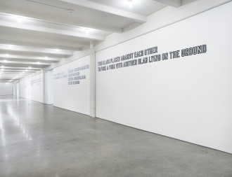 Three gallery walls along a corridor feature white text outlined in black. The nearest text reads: 