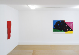 Two colorful abstract paintings hang on two adjoining white walls.