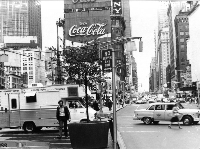 A busy metropolitan intersection is filled with cars and pedestrians in this black-and-white image.